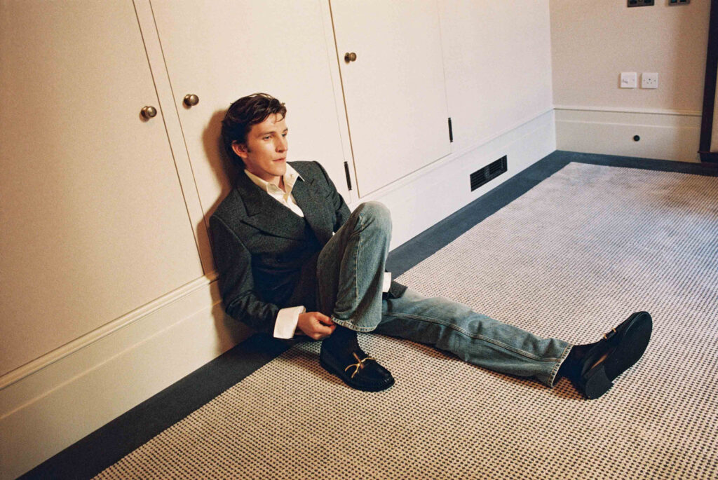 Ewan Mitchell Is Odessa A’zion’s Uncle Now Ewan Mitchell sitting on a white carpet leaning against a built in dresser
